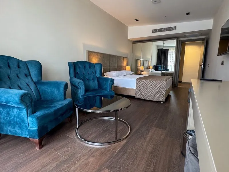 Moderna hotelska soba z modrimi naslanjači in udobno posteljo