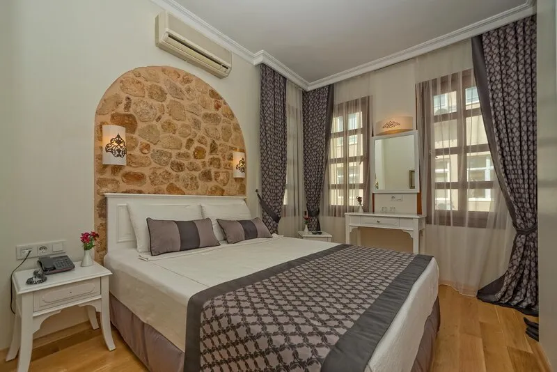 Elegantna spalnica z izpostavljenim kamnitim zidom in belim pohištvom