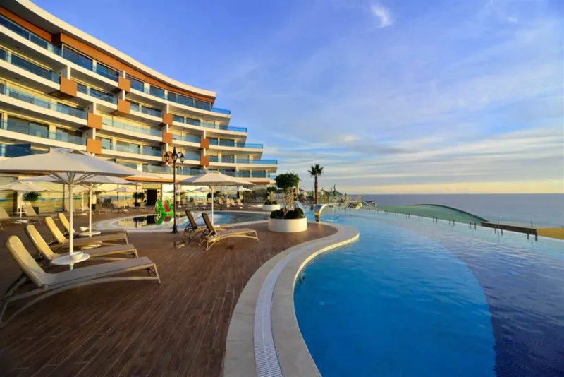 Zunanji infinity bazen s pogledom na morje ob sončnem zahodu